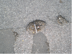 Small, shallow pothole in a road
