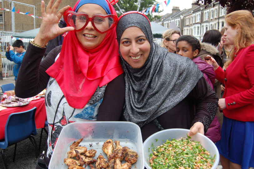 Two women holding trays of food at a street party