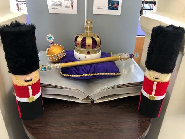 Table decorated with models of soldiers and a cushion with model crowns on it.