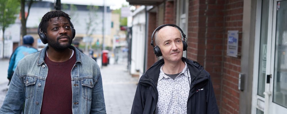 Aundre Goddard and Richard Bentley walking on a street with headphones on