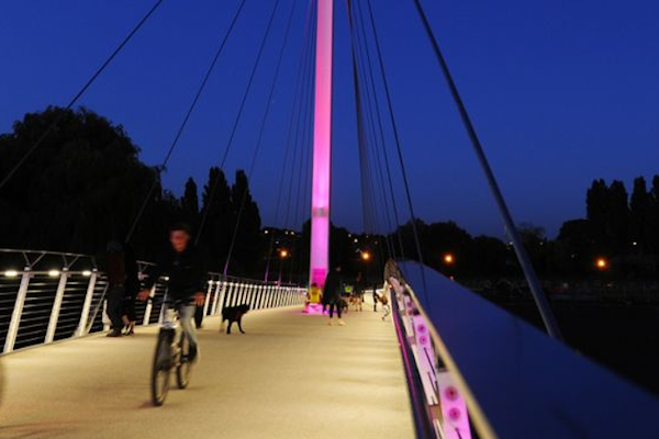 Christchurch Bridge at night with cyclists and walkers using it.