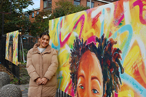photo of a woman stood next to a street mural