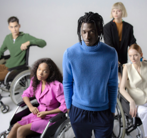 Man standing in foreground, three people in wheelchairs and someone standing behind him.