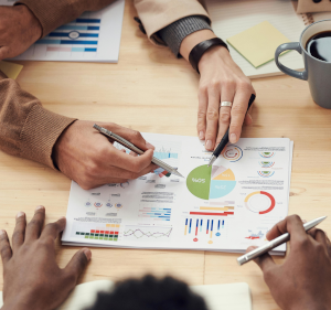 Printed charts with hands with pens pointing at them.