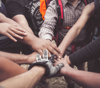 Hands from an unseen group joined in the centre of a group.