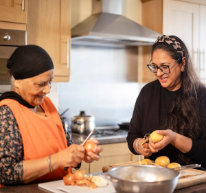 Two women sat at a table preparing vegetables.