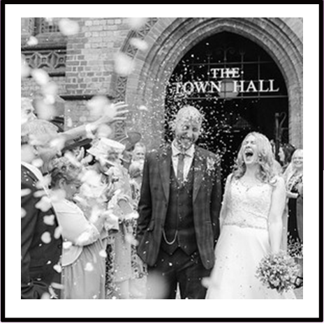 Bride and groom leaving Town Hall with confetti being thrown over them.