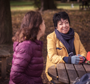 Two women sat at a table in a park.