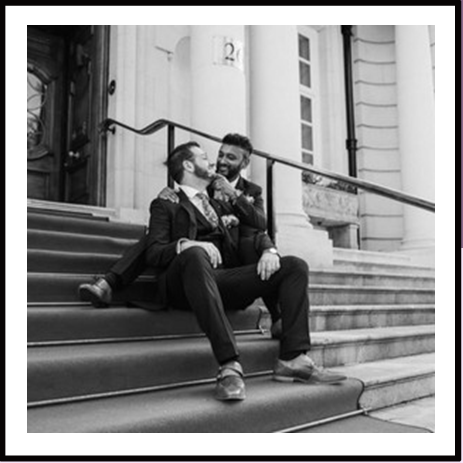 Groom and groom sat on steps outside venue that isn't the Town Hall.