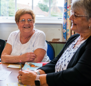 Two older women sat at a table laughing.