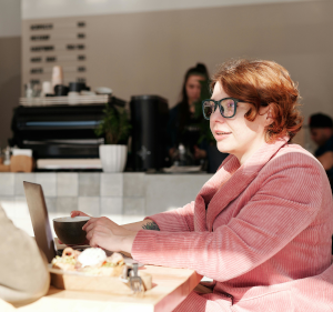 Woman sat at a table with a laptop in a coffee shop.