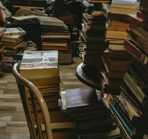 Piles of books on floor and chair.