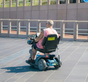 Person on a mobility scooter in a car park.