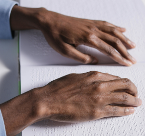 Hands reading Braille in book.