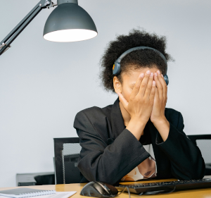 Woman sat at a desk with her head in her hands.