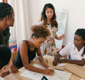 Group of people working on a large sheet of paper around a table.