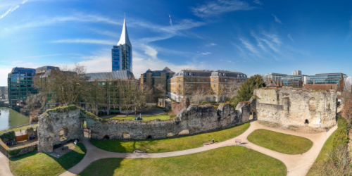 Wide screen photo showing Reading Abbey in the foreground and modern town centre building in the background.