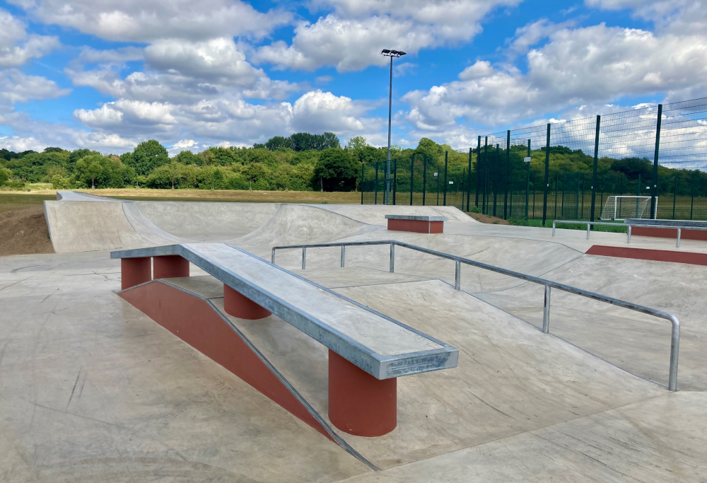 Shows ramps, pipes and benches in skateboard park.