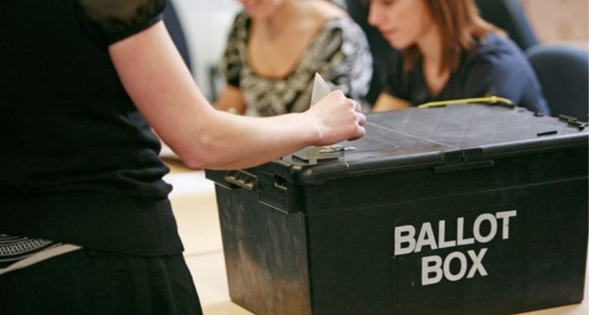 photo of someone putting paper into a ballot box