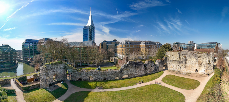 Wide screen photo showing Reading Abbey in the foreground and modern town centre building in the background.