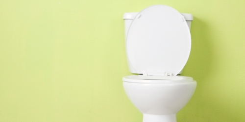 A white toilet with the lid up against a light green wall.