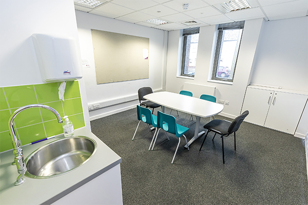 photo of the meeting room showing a table, chairs and a sink