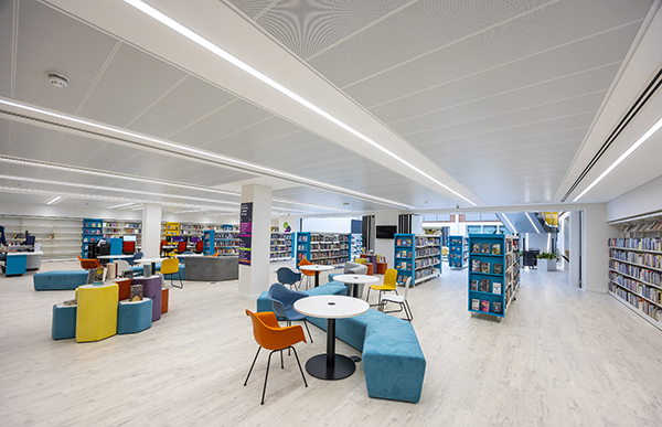Bright, open-plan library with bookshelves, study tables, colourful seating, and flexible spaces for reading, studying, and relaxing.