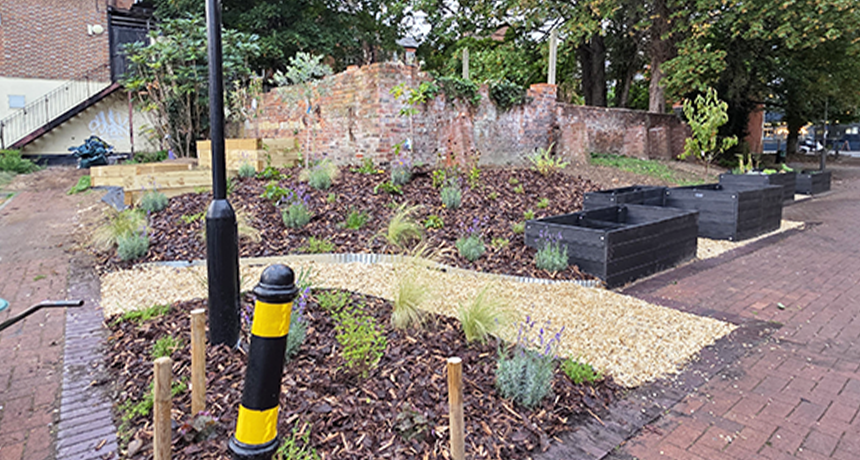 new community garden showing a stone path, bark chippings, large planters, shrubbery and small trees