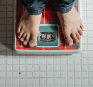 Overhead photo of feet on weighing scales on a tiled floor.